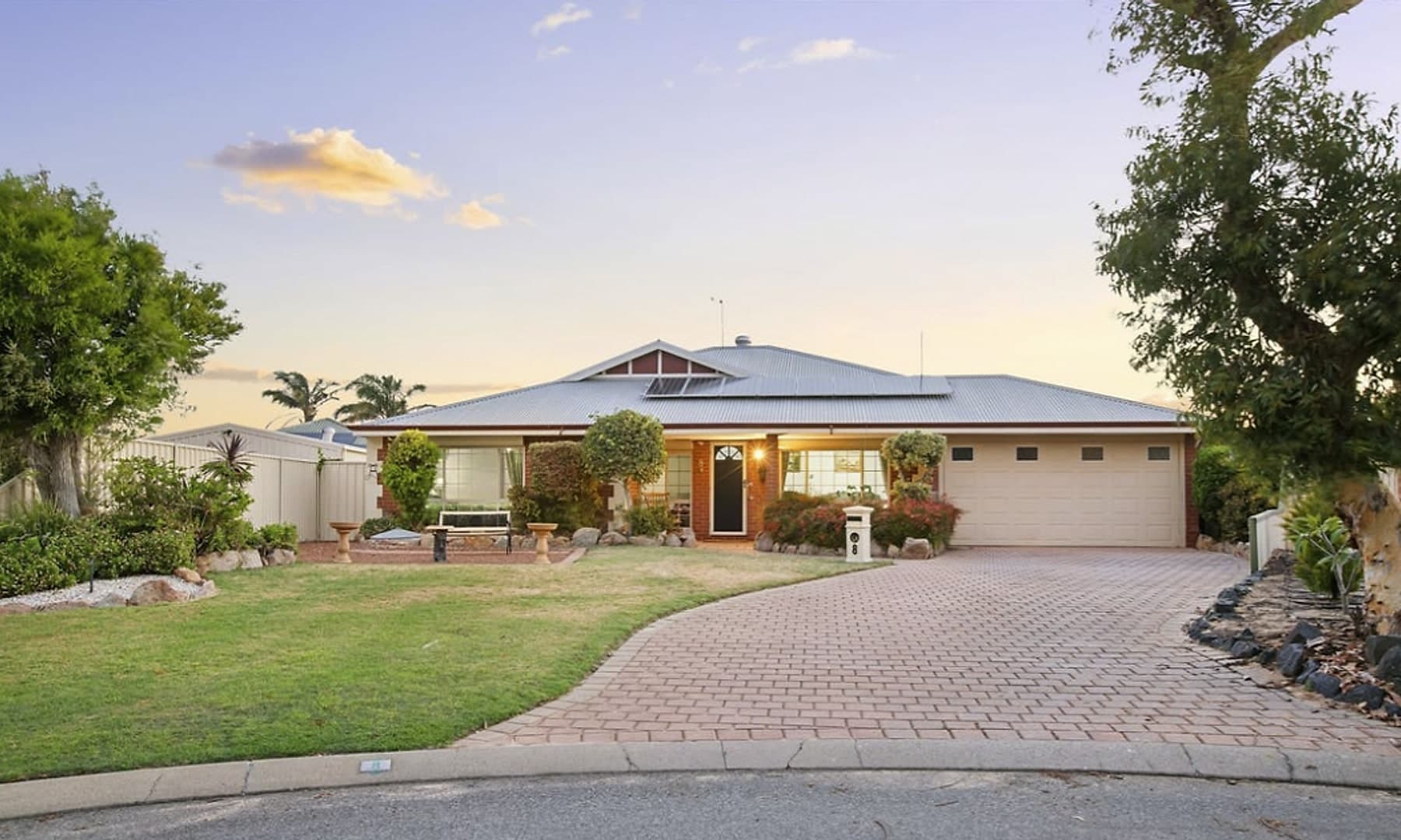 The Waikiki home from the street, a single storey brick house on a cul de sac with a paved driveway and a double garage.
