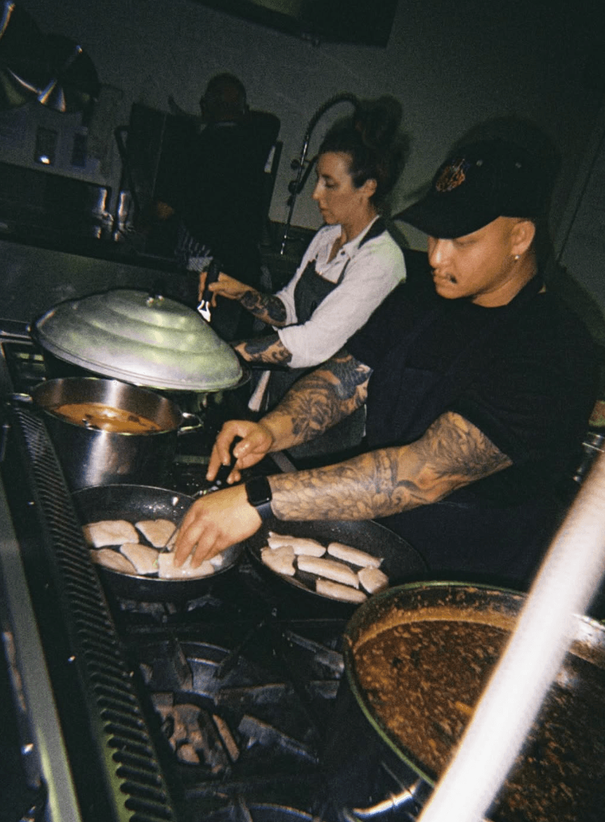 Two chefs cooking over open flame in the Magnolia BBQ kitchen, Victoria Park.